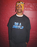 Skateboarder Chucky Lane wearing the Stingwater "Do a Candyflip" T-shirt in black with bold blue font and white icy snow capped letters with a red brick backdrop in NYC